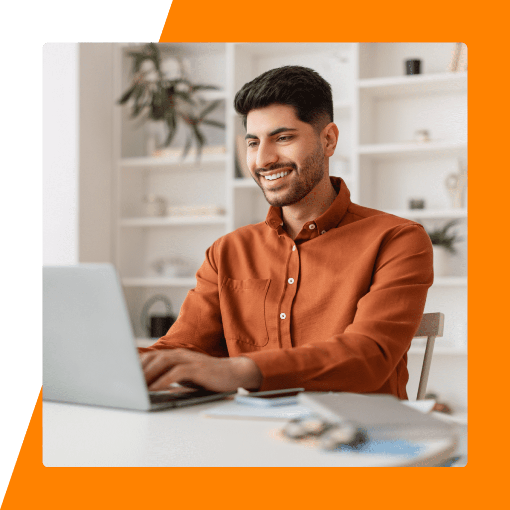 Smiling Male Employee Working on Laptop Computer in Home Office